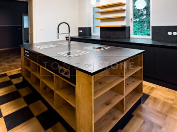 Pracovní deska kuchyňského ostrůvku ze žuly Nero Assoluto Zimbabwe (trattato). Součástí ostrůvku jsou 4 varné desky s horní montáží a baterií uprostřed. Pracovní deska kuchyňského ostrůvku ze žuly Nero Assoluto Zimbabwe (trattato). Součástí ostrůvku jsou 4 varné desky s horní montáží a baterií uprostřed.