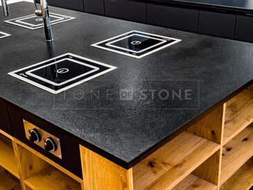 Detail varného ostrůvku ze žuly Nero Assoluto Zimbabwe (trattato), v pozadí kuchyňská deska a parapet ze stejného přírodního kamene. Zakázková výroba TONE OF STONE Detail varného ostrůvku ze žuly Nero Assoluto Zimbabwe (trattato), v pozadí kuchyňská deska a parapet ze stejného přírodního kamene. Zakázková výroba TONE OF STONE