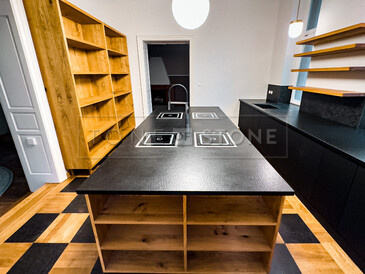 Pracovní ostrůvek ze žuly Nero Assoluto Zimbabwe (trattato) s osazenými 4 varnými deskami s horní montáží a baterií uprostřed. Ze stejného přírodního kamene je i pracovní deska v pozadí. Pracovní ostrůvek ze žuly Nero Assoluto Zimbabwe (trattato) s osazenými 4 varnými deskami s horní montáží a baterií uprostřed. Ze stejného přírodního kamene je i pracovní deska v pozadí.