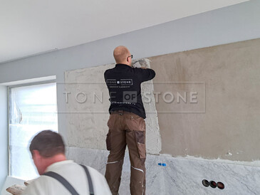 Práce při obložení stěny přírodním mramorem Bianco Carrara Práce při obložení stěny přírodním mramorem Bianco Carrara