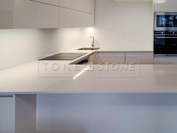 Bílá kuchyně s kamennou pracovní deskou z umělého kamene Technistone Noble Supreme White. Zakázková výroba TONE OF STONE. Bílá kuchyně s kamennou pracovní deskou z umělého kamene Technistone Noble Supreme White. Zakázková výroba TONE OF STONE.