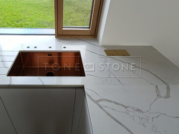 Rohový spoj kuchyňské desky z Technistone Crystal Calacatta Silva, jejíž součástí je i integrovaná elektrická zásuvka a měděný dřez se spodní montáží. Zakázková výroba TONE OF STONE. Rohový spoj kuchyňské desky z Technistone Crystal Calacatta Silva, jejíž součástí je i integrovaná elektrická zásuvka a měděný dřez se spodní montáží. Zakázková výroba TONE OF STONE.