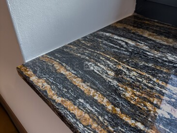 Detail kresby kamenného parapetu ze žuly Magma Black a jejího výrazného žilkování v černo zlatých odstínech Detail kresby kamenného parapetu ze žuly Magma Black a jejího výrazného žilkování v černo zlatých odstínech