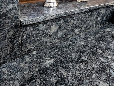 Kamenná kuchyňská deska a obklad stěn za kuchyňskou linkou s přechodem na obložení okenního parapetu, přírodní kámen - Žula STEEL GRAY s kartáčovaným povrchem, detail přechodu Kamenná kuchyňská deska a obklad stěn za kuchyňskou linkou s přechodem na obložení okenního parapetu, přírodní kámen - Žula STEEL GRAY s kartáčovaným povrchem, detail přechodu